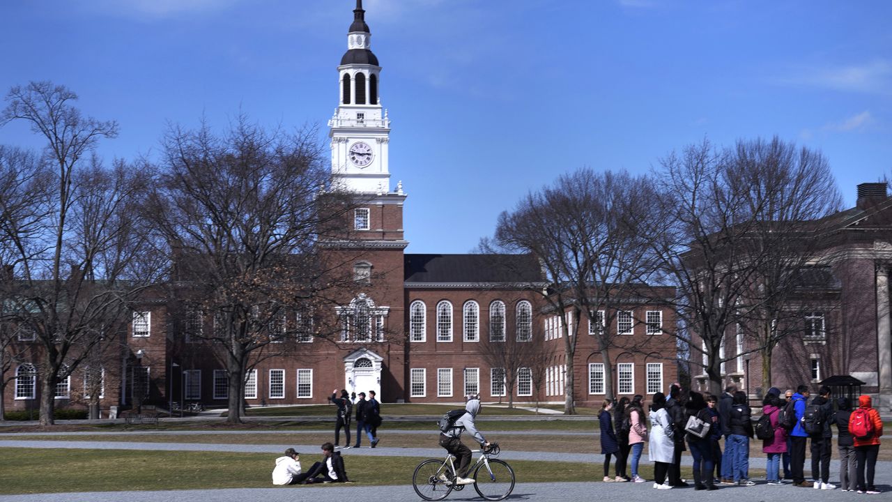 A bicyclist passes a college tour group outside the Baker Library at Dartmouth College on April 7 in Hanover, N.H.