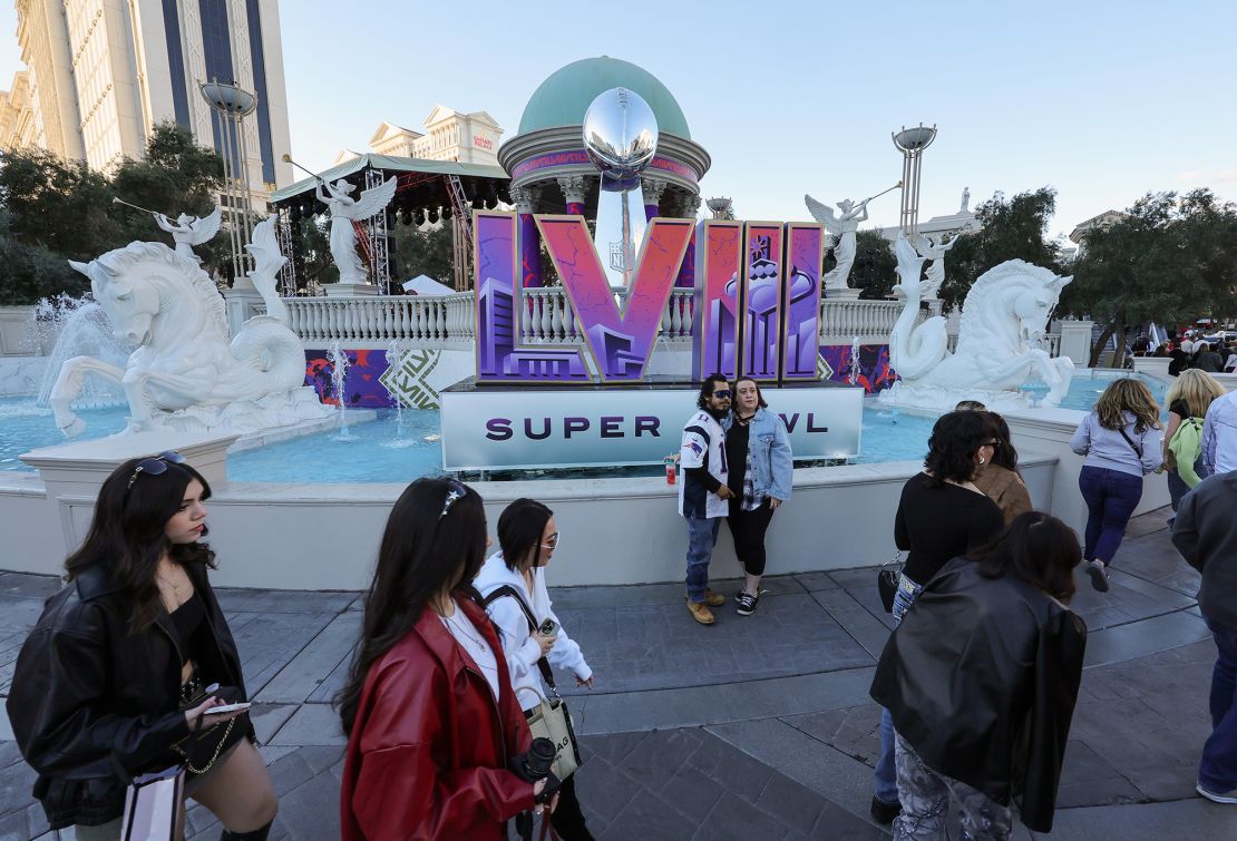 Visitors pose in front of a Super Bowl LVIII logo and an oversized replica of the Vince Lombardi Trophy on the Las Vegas Strip in front of Caesars Palace on February 3, 2024.